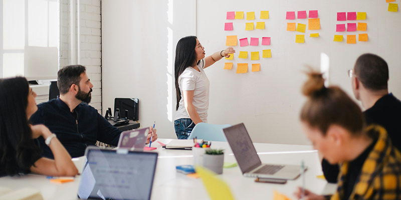 A woman placing sticky notes on a White board