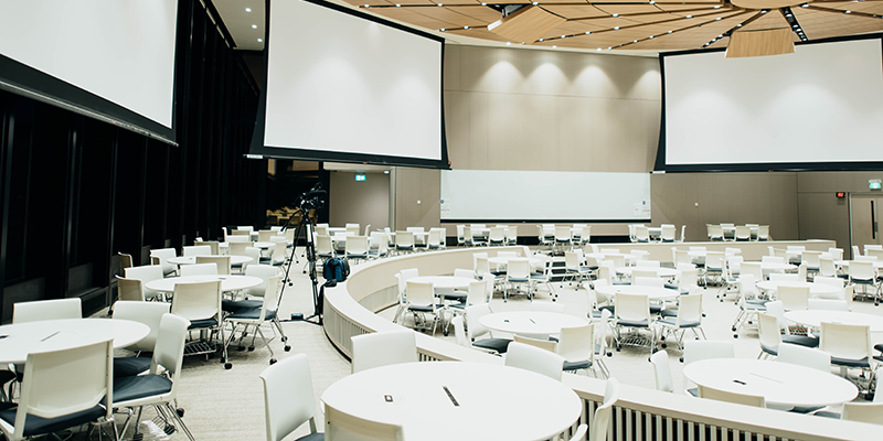 A photo of an empty room with projector screen and tables