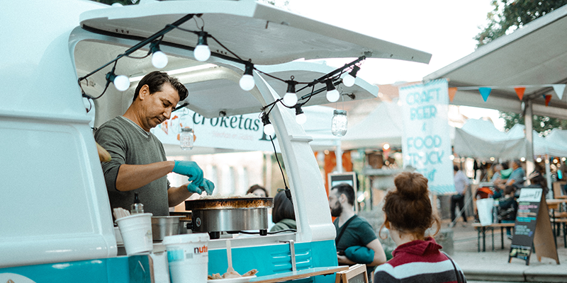 A woman placing an order for food to a man standing in a food truck