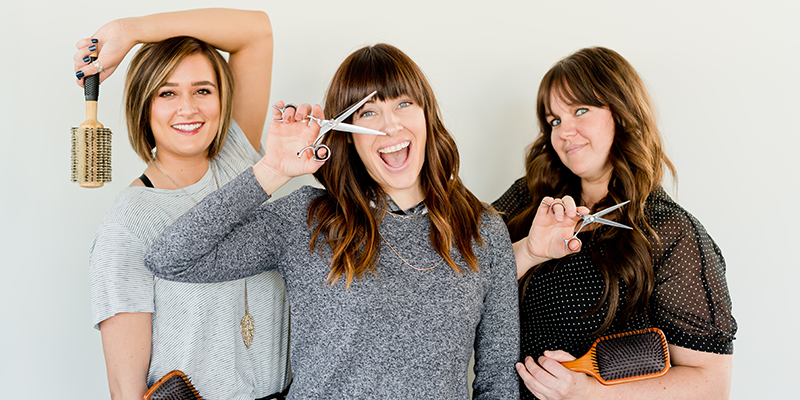 Three hairstylists holding salon equipment
