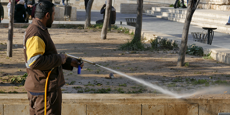 A man in a uniform cleaning a wall using a pressure washer
